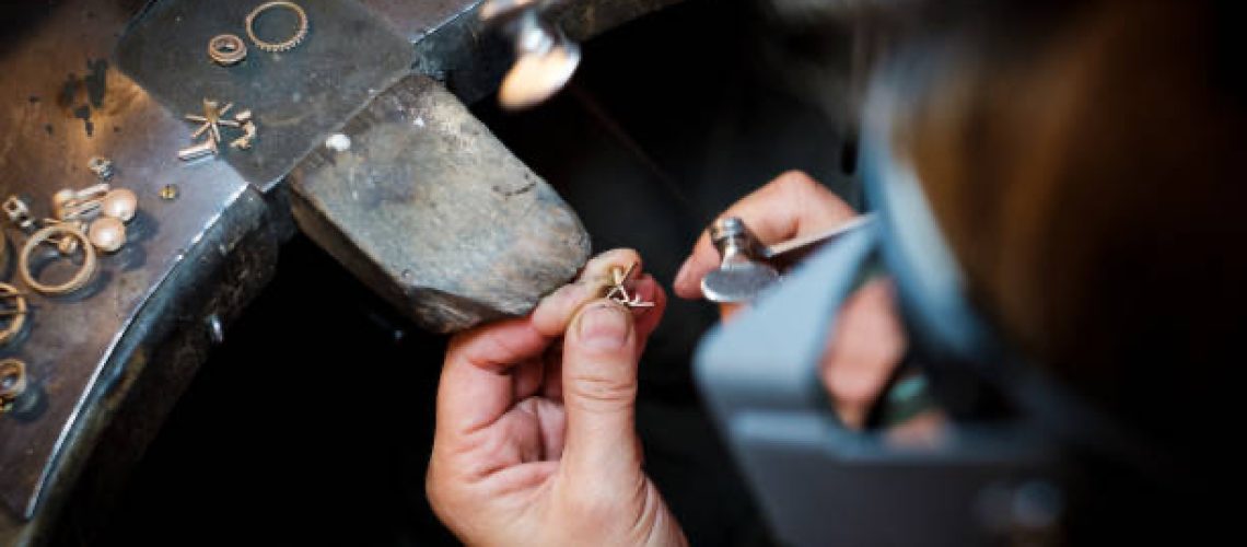 Jeweler saws with small saw at a gold ring in an authentic jewellery workshop